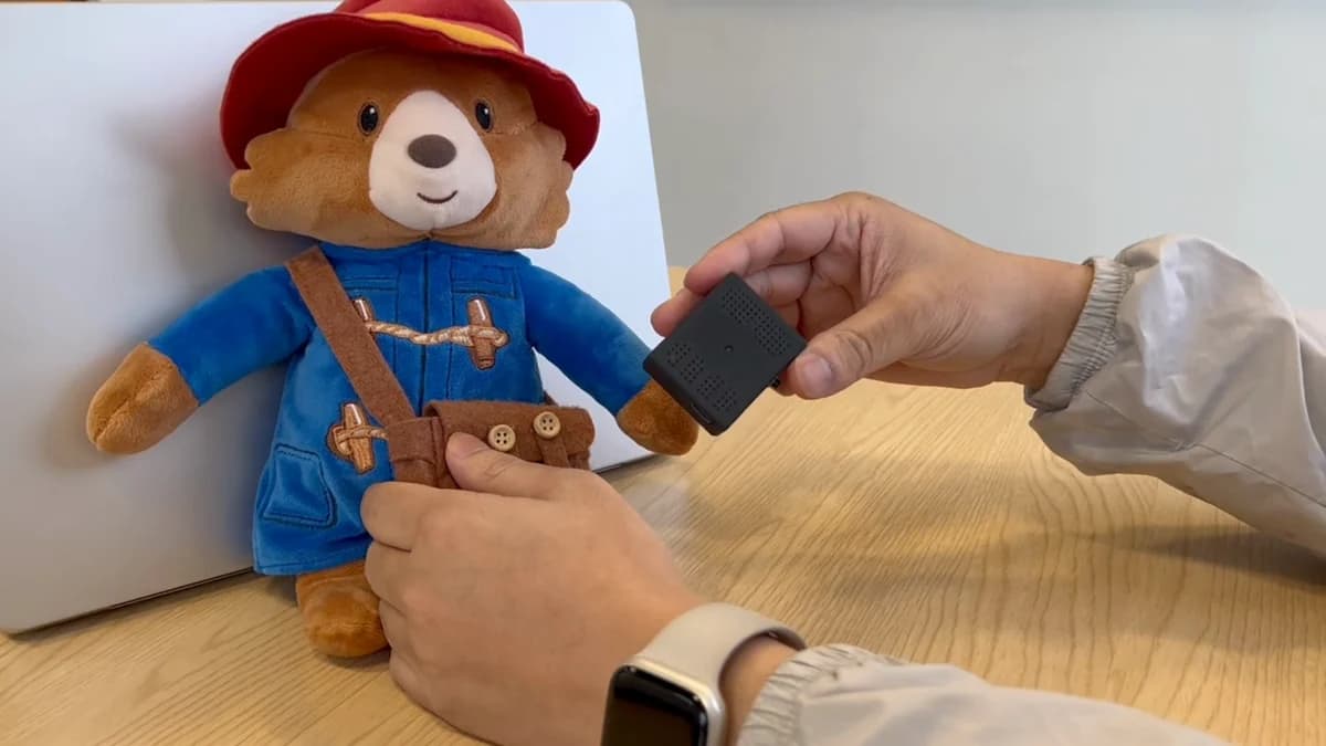The Starmoon device, a small black board, held beside a teddy bear it fits inside.
